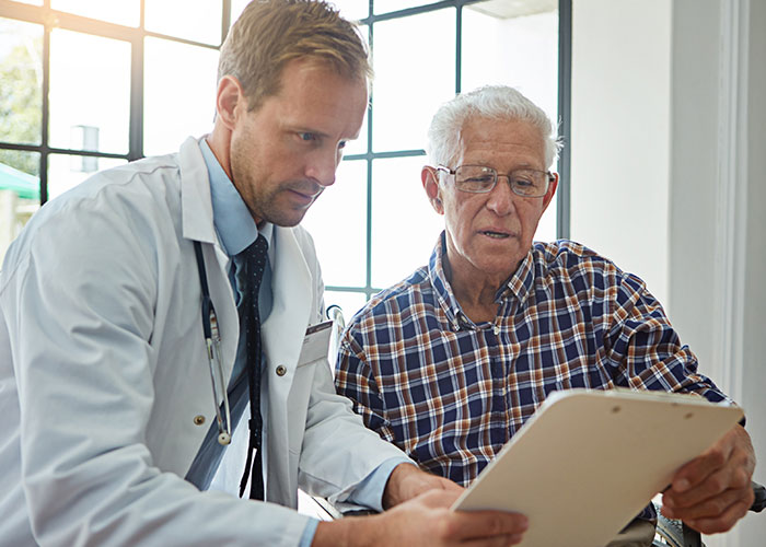 Doctor explaining medical document to elderly man in a plaid shirt, discussing organ donation and patient care options.