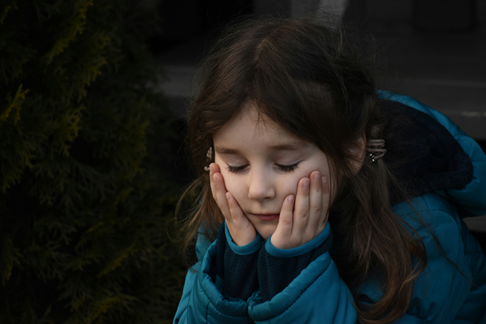 Young girl looking sad and thoughtful outdoors, illustrating concerns about family blacklisted local babysitters.