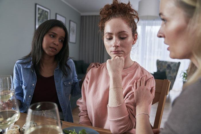 Three women sit at a table, one upset, others comforting her in a tense family confrontation about trial wife issues. Three women sit at a table, one upset, others comforting her in a tense family confrontation about trial wife issues.