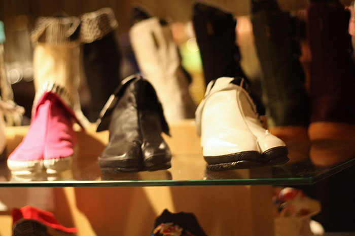Various fashion trend boots displayed on a glass shelf highlighting popular fashion trend propaganda people reject.
