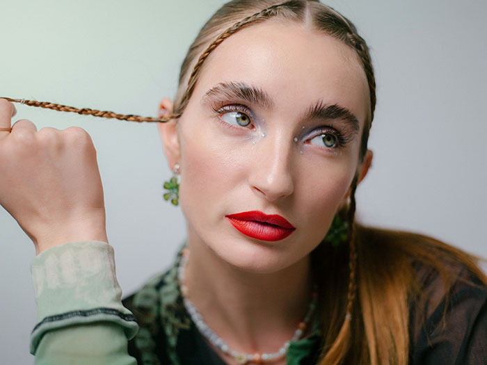 Young woman with bold red lipstick and braided hair, illustrating fashion trend propaganda people refuse to follow.