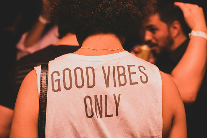 Person wearing a sleeveless shirt with good vibes only text, highlighting fashion trend propaganda refusal context.
