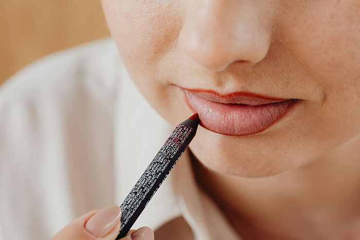 Close-up of a person applying lip liner pencil, illustrating a fashion trend people refuse to fall for.