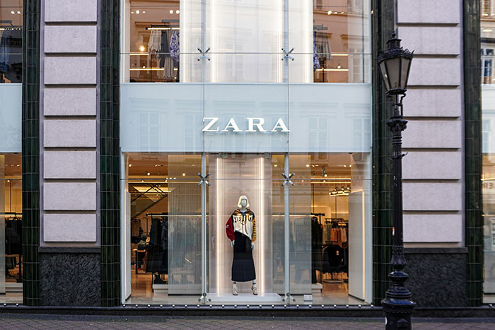 Zara store window display featuring a mannequin showcasing current fashion trends in a modern retail setting.