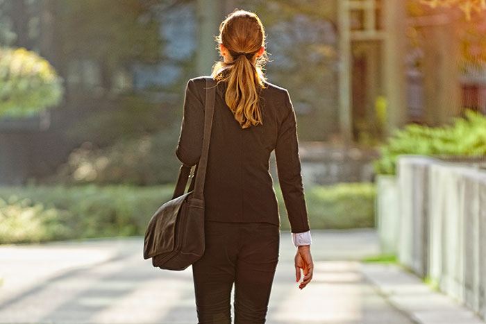 Woman walking away from office building during sunset symbolizing quitting a job after a horrific job experience.