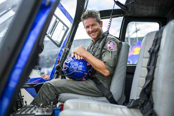 Smiling daredevil skydiver in flight suit holding blue helmet inside helicopter before viral final jump accident. Smiling daredevil skydiver in flight suit holding blue helmet inside helicopter before viral final jump accident.