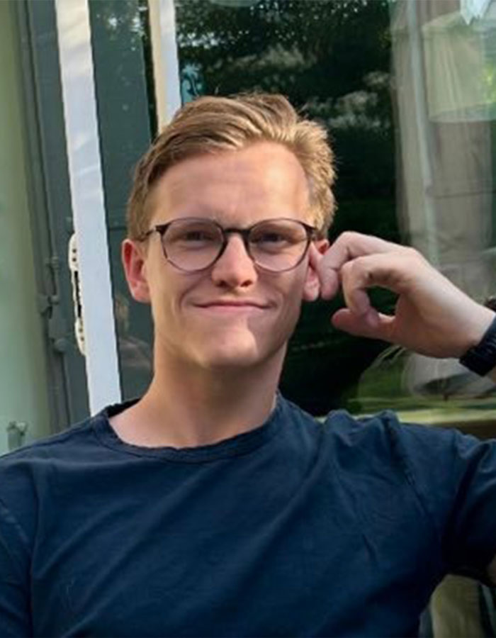 Young man wearing glasses and a dark shirt, smiling casually outdoors, related to astronomer CEO Andy Byron incident.