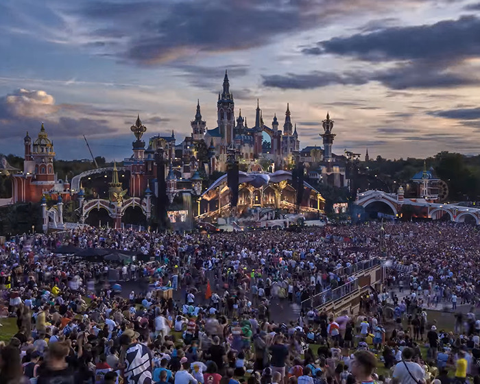 Massive fire engulfs main stage at Tomorrowland festival with large crowd gathered before the event opening at dusk.