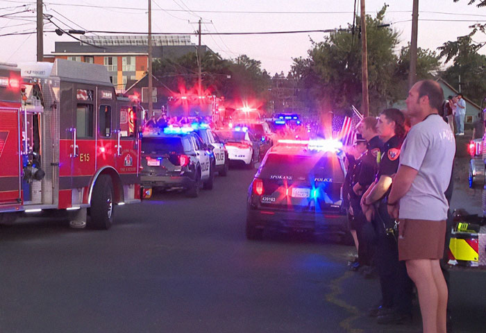 Emergency responders including police and firefighters stand with vehicles flashing lights at a scene linked to Idaho teen sniper incident