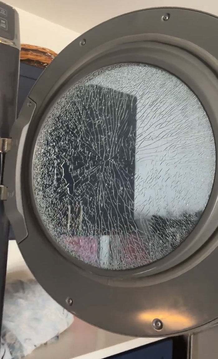 C*****d glass door of a washing machine showing a funny unfortunate situation of forgotten item damage.