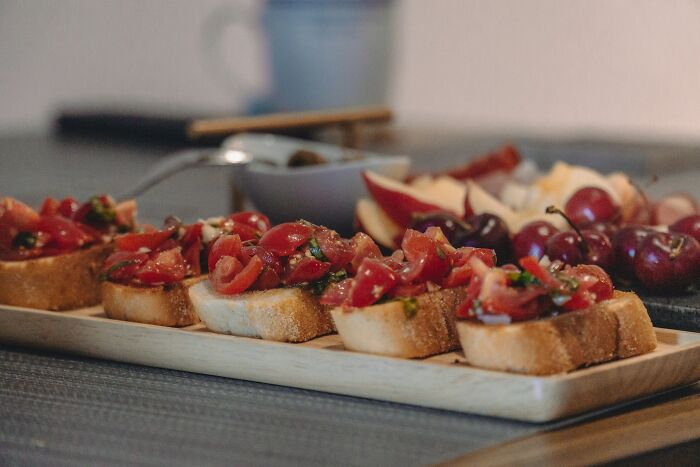 Close-up of bruschetta appetizers with fresh tomatoes and herbs on a wooden board, showcasing surprising U.S. travel foods.