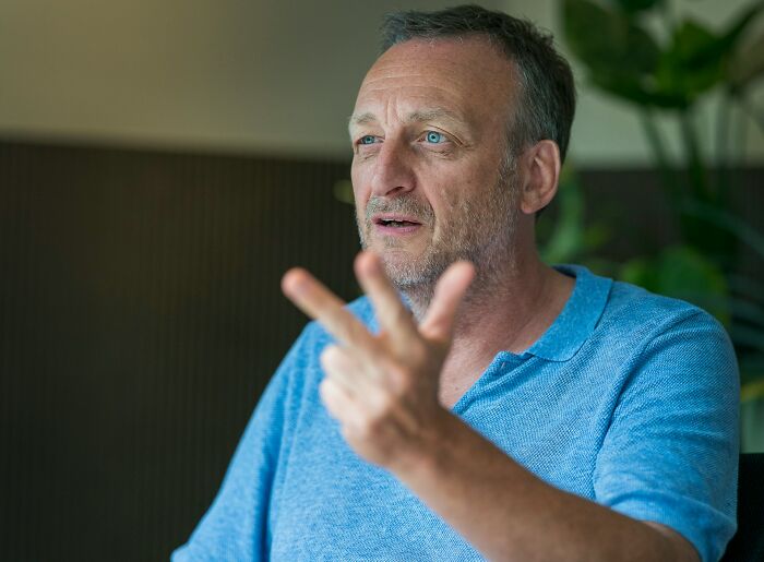 Middle-aged man in blue shirt expressing frustration, illustrating arrogance and regret in a casual indoor setting.