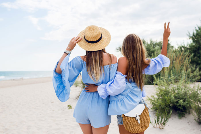 Two women on a beach vacation, one wearing a straw hat, highlighting a friendship trip causing family rift. - 12