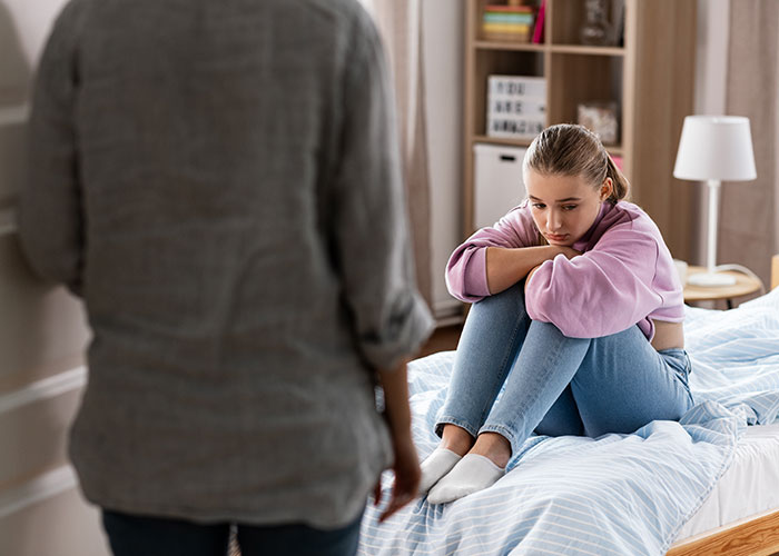 Young woman sitting on bed looking upset while another person stands nearby, reflecting conflict and revenge after theft incident. - 51