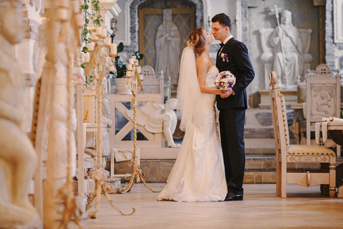 Bride and groom kissing at ornate wedding venue, symbolizing friend’s wedding and payment dispute story. - 6