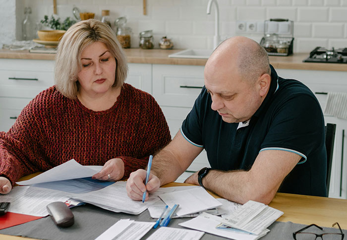 Person upset friend doesn’t pay more after winning lottery, discussing finances and bills at kitchen table. - 9