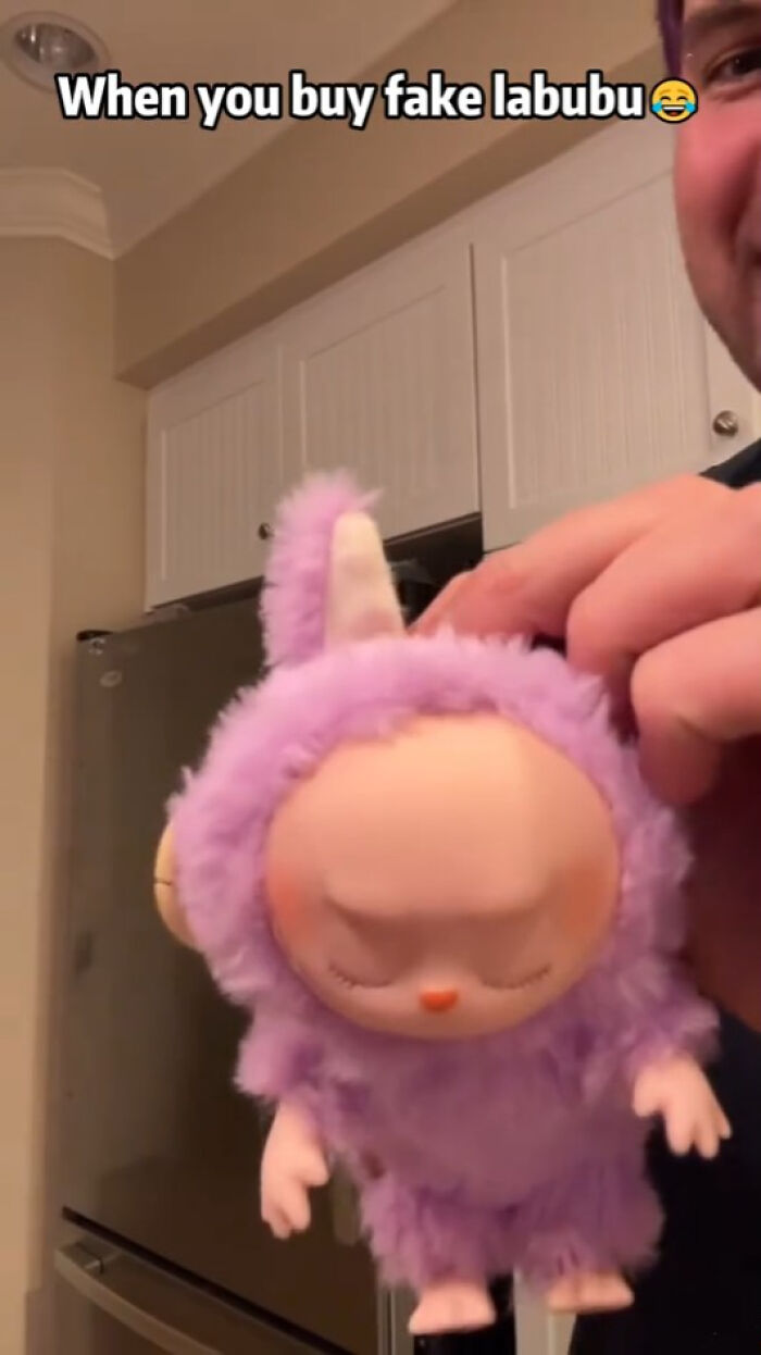 Man holding a creepy fake Labubu toy in a kitchen, highlighting disturbing Labubu fakes that might give nightmares.