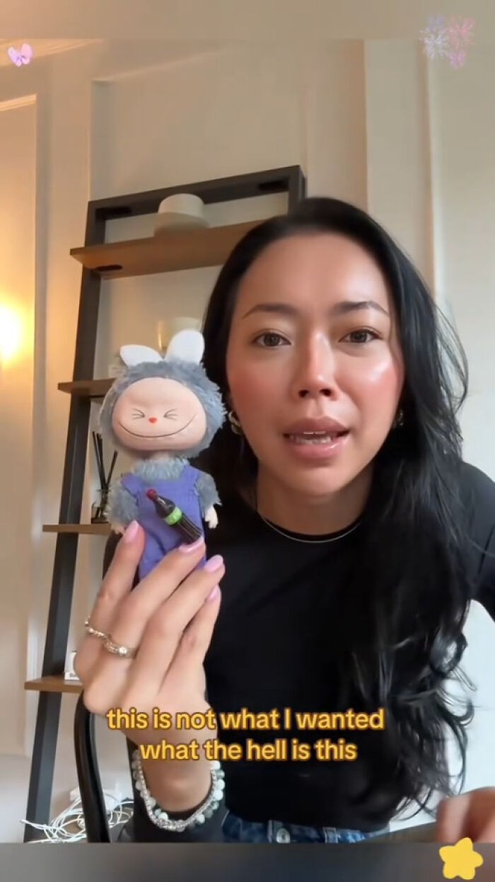 Woman holding a creepy Labubus fake doll indoors with text expressing disappointment about the item received.