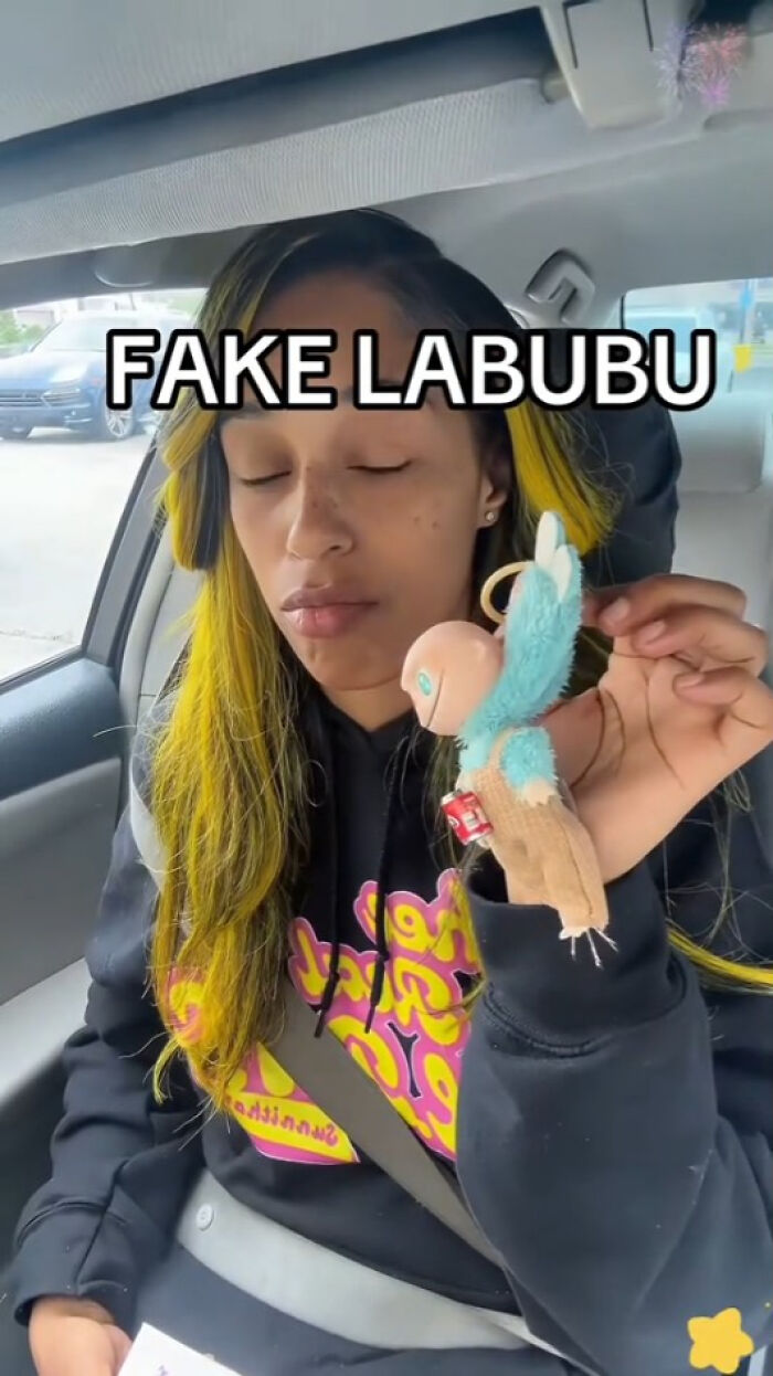 Woman in car holding a creepy fake Labubu doll with yellow hair and closed eyes showing nightmare-inducing fakes.