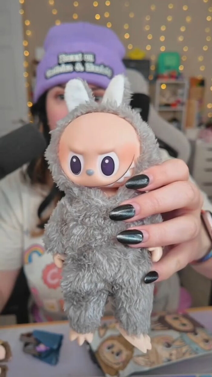 Person holding Labubus doll fake in furry costume with creepy expression and large eyes, eerie toy close-up.