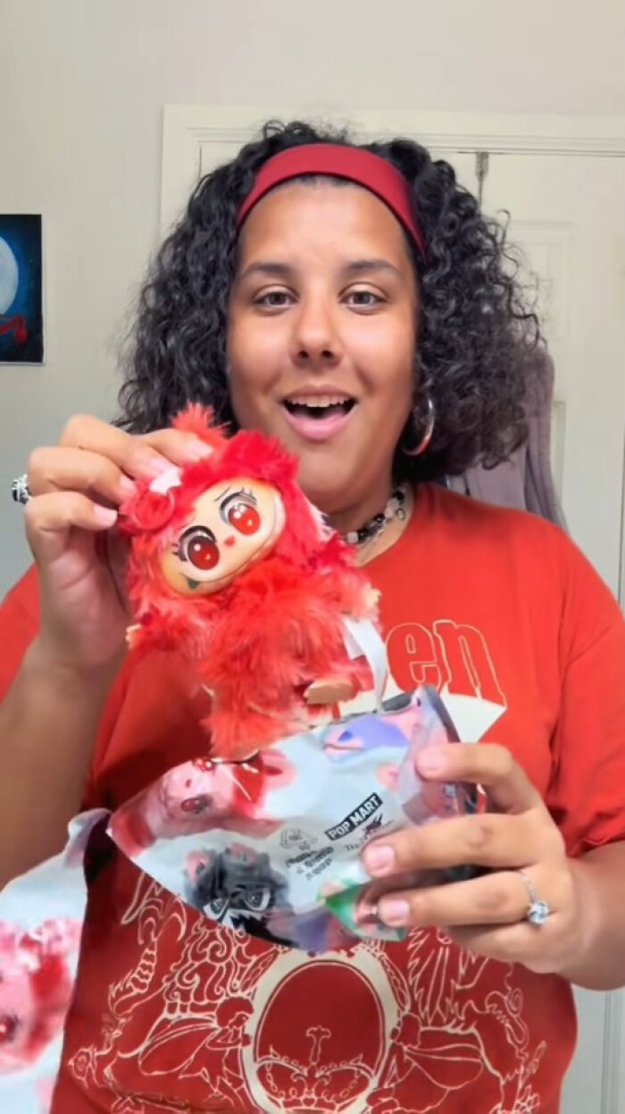 Person holding a creepy Labubus fake doll with bright red fur and large eyes, showcasing nightmare-inducing toys.