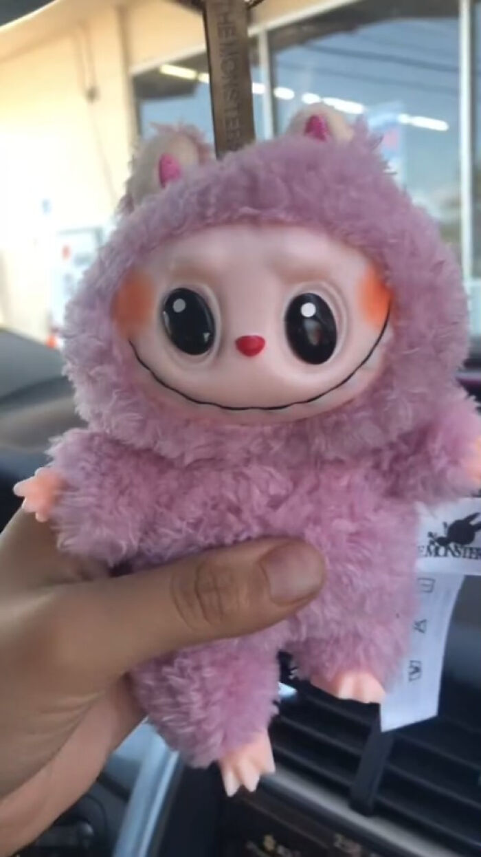 Hand holding a creepy plush toy with large eyes and a wide smile, part of Labubus fakes collection.