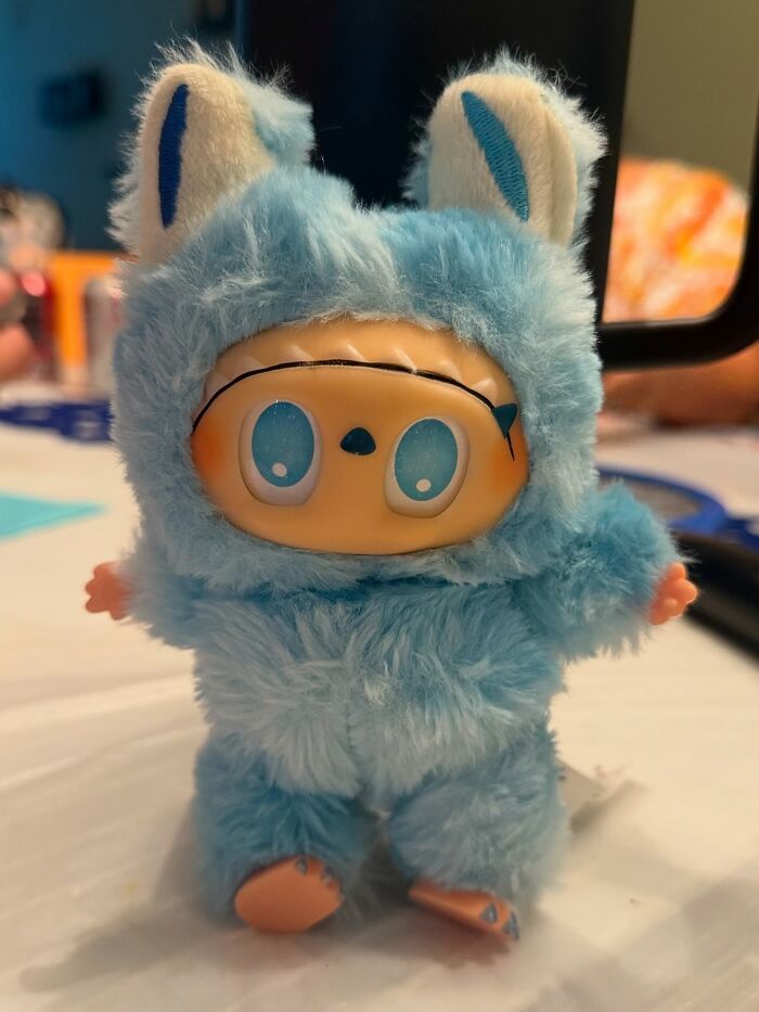 Small Labubus figure in a fuzzy blue animal costume with large eyes, representing creepy and nightmare-inducing fakes.