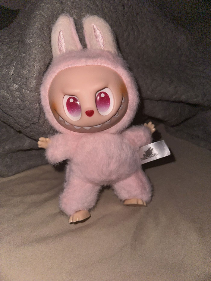 Creepy Labubus doll in pink fuzzy bunny costume with sharp teeth and large eyes, one of the nightmare-inducing fakes.