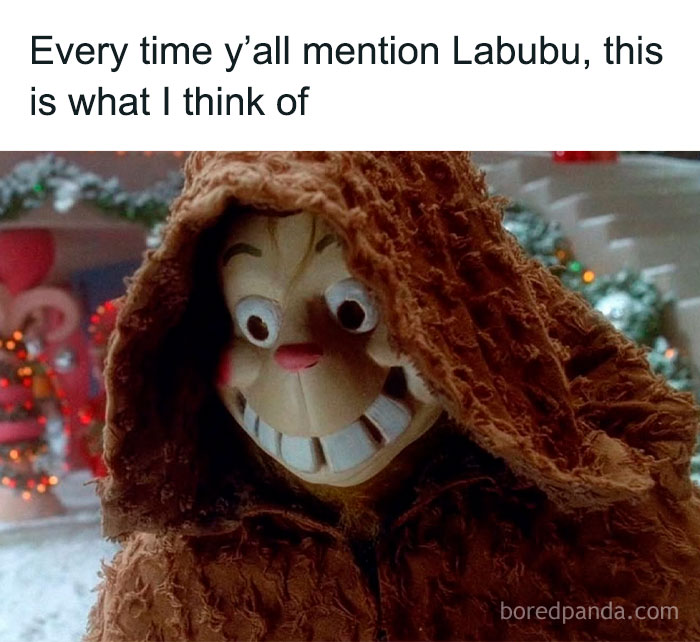 Creepy doll with wide eyes and big grin wearing a tattered brown hooded cloak, popular in Labubu doll memes online.