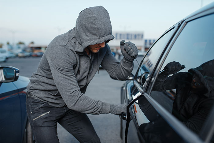 A man in a gray hoodie attempting to break into a car, symbolizing defendants failing miserably in court.