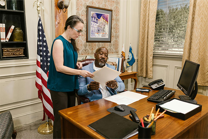 Lawyers consulting with defendant in office, reviewing legal documents and discussing court case strategy together.