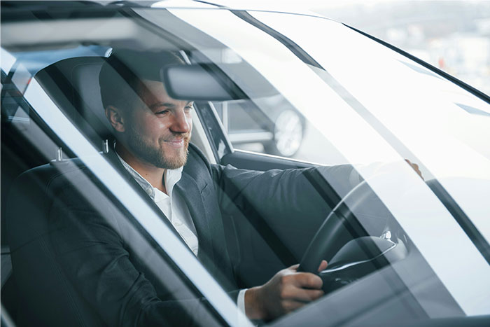 Smiling lawyer driving a car, dressed in a suit, representing lawyers and defendants failing miserably in court concept.