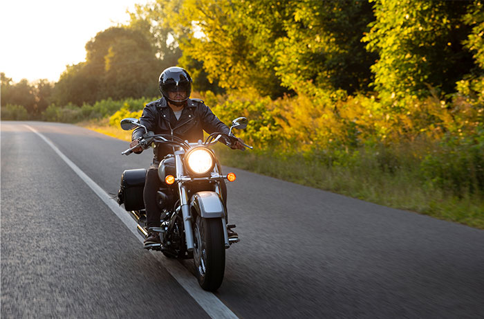 Motorcyclist wearing a helmet riding on a scenic road, symbolizing lawyers and defendants failing miserably in court.