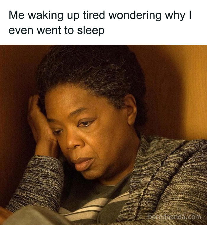 Tired person sitting against a wall with a weary expression, relatable meme about waking up exhausted.