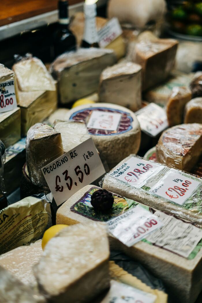 Assorted cheeses wrapped and labeled with prices at a market stall, highlighting items on the brink of collapse. - 18