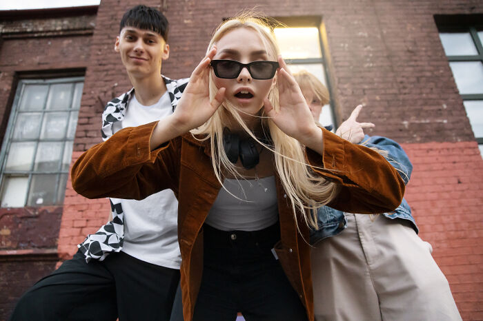 Three Gen Z friends posing confidently outdoors, showcasing unique styles and playful ways to hand out compliments.