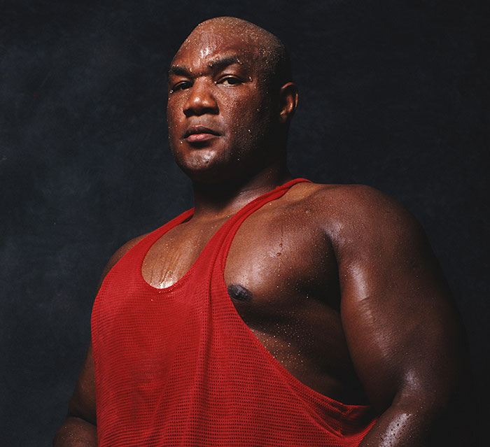 Athlete wearing a red tank top, sweating and posing against a dark background, symbolizing stars we've lost this year.