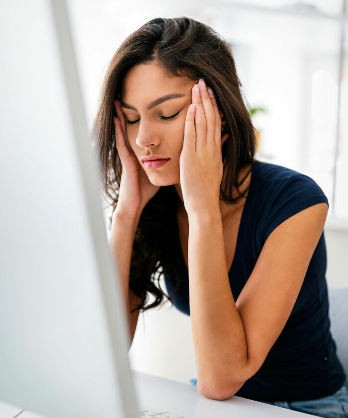 Young woman showing signs of stress and frustration at desk, illustrating toxic femininity behaviors concept. - 19