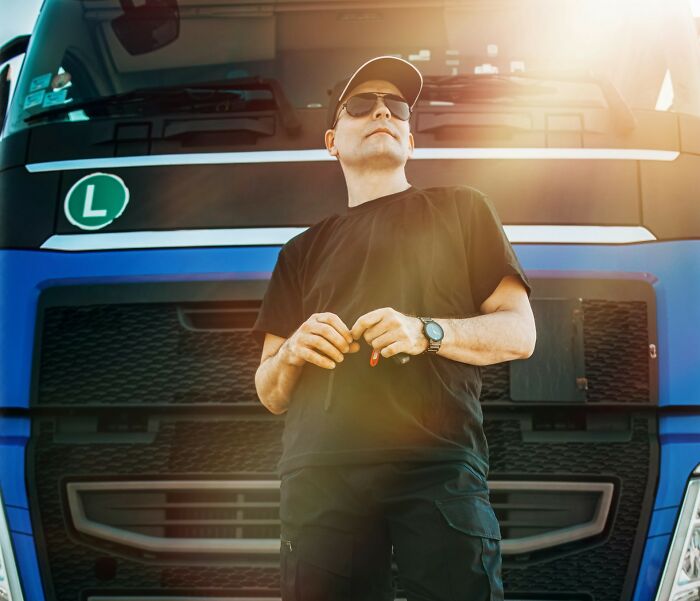 Man standing confidently in front of a large truck with sunglasses, illustrating what makes a man instantly unattractive.