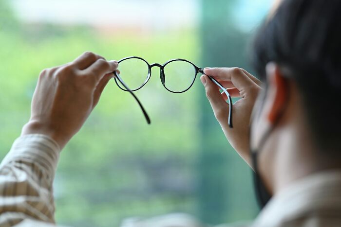 Person holding eyeglasses up to the light, illustrating unusual items found in or on patients that made medical professionals gasp