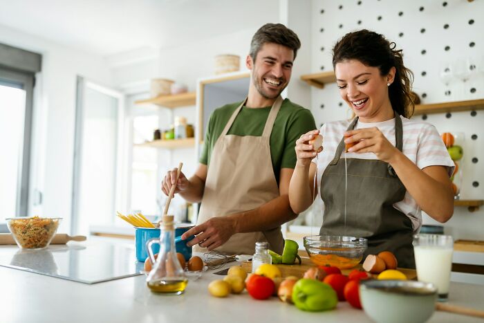 Happy couple cooking together in a modern kitchen, demonstrating calm communication and teamwork skills during meal prep.