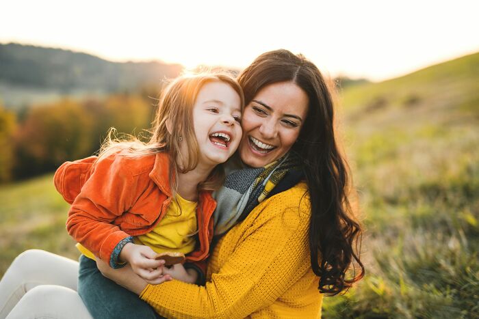 Mother and daughter laughing outdoors in a field, illustrating contrasting themes related to toxic femininity behaviors. - 40