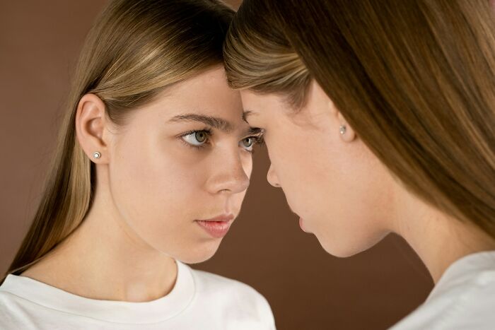 Two young women facing each other closely, demonstrating the challenge of communicating calmly in tense situations.
