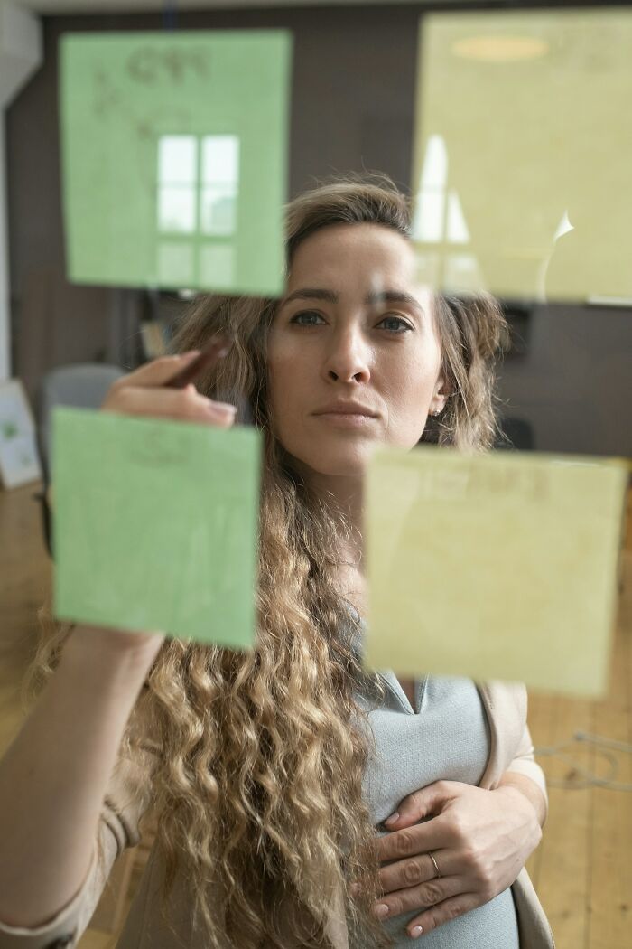 Woman with curly hair brainstorming ideas on sticky notes on glass, focusing on internet issues and potential collapse risks. - 2