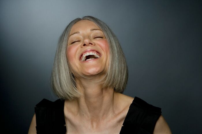 Older woman with gray hair laughing joyfully, representing life experiences of older people after divorce. - 2