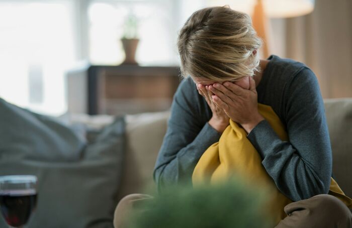 Woman sitting on a couch, covering her face in distress, illustrating disturbing things people overheard someone say.