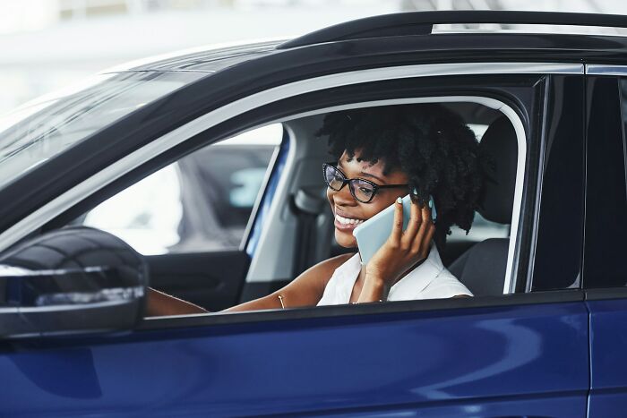 Smiling woman talking on phone inside a blue car representing people who left their partner due to shenanigans.