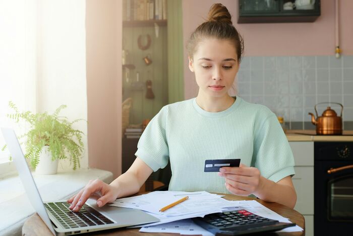 Young woman managing finances at kitchen table, reflecting on stories from married people who wish they were single.