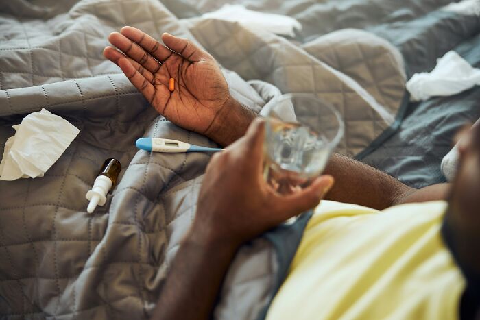 Person resting in bed holding a pill and glass of water, illustrating people share reasons not divorced concept.
