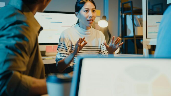 A woman explaining feminist small daily wins during a discussion with colleagues in an office setting.